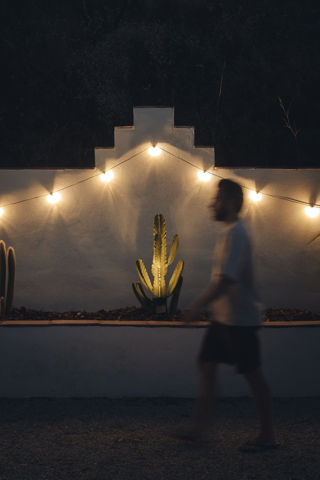 Whitewashed garden wall lit by festoon lights at night